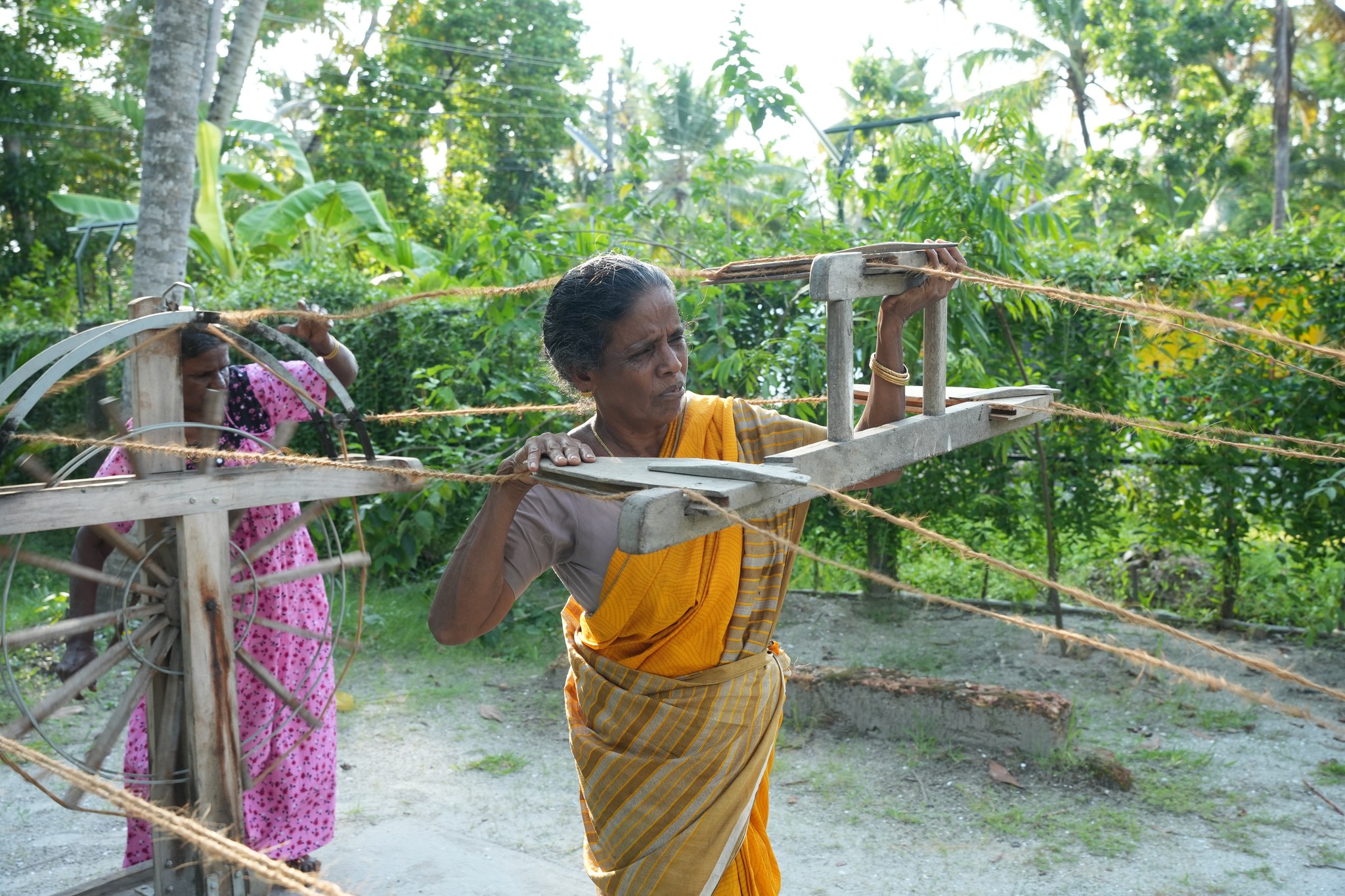 Local artisans spinning coconut fibre into coir rope using traditional wooden tools