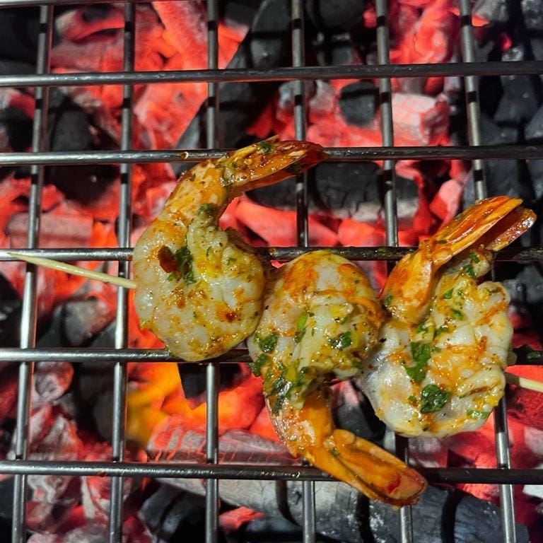 Seasoned prawns grilling over glowing charcoal